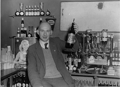 055 P&amp;H32; Pearse Digan holding a bottle of Egan's No.8 Whiskey in the Tullamore Rugby a. Soccer Club 1959